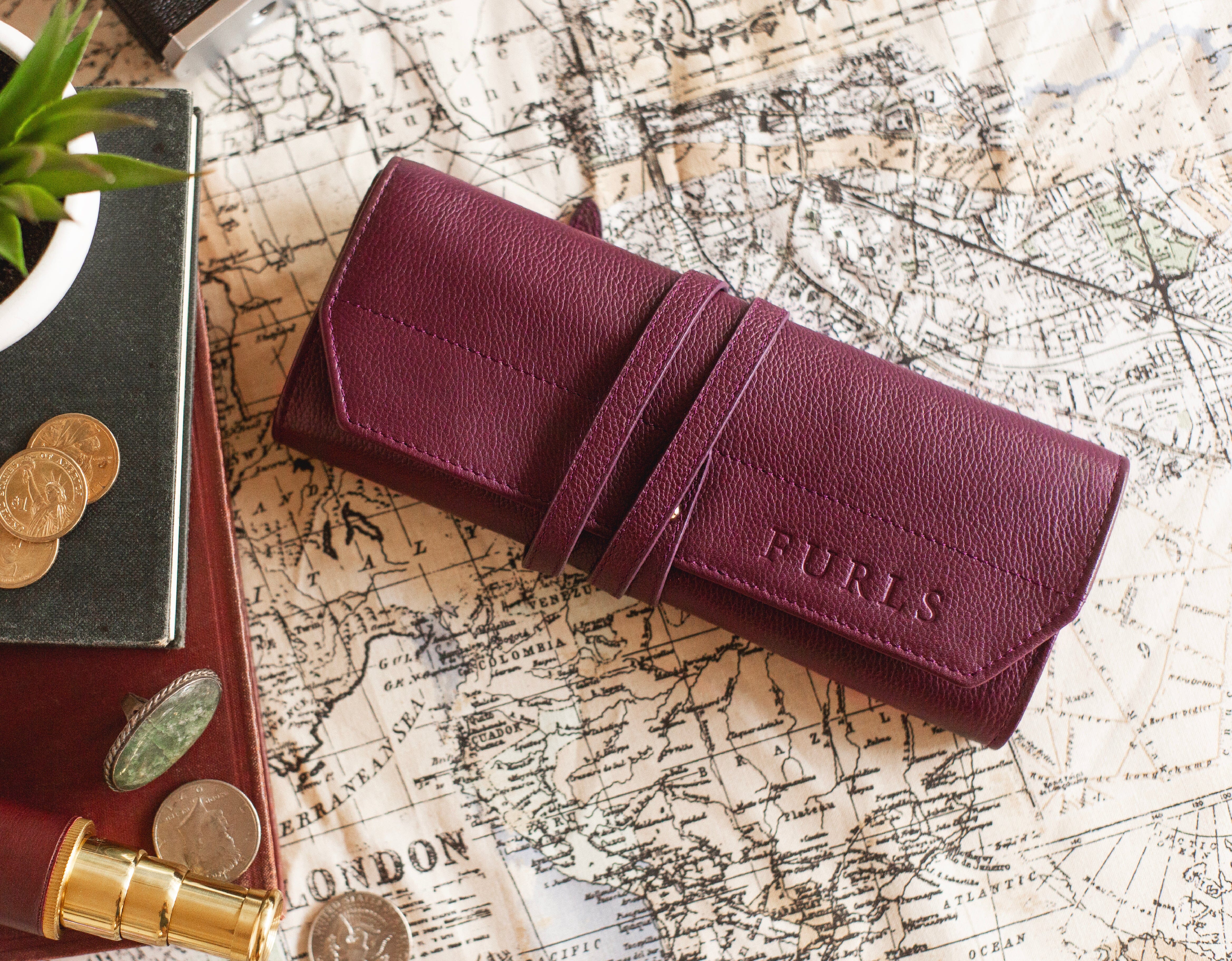 Plum leather roll up hook case on a map background.